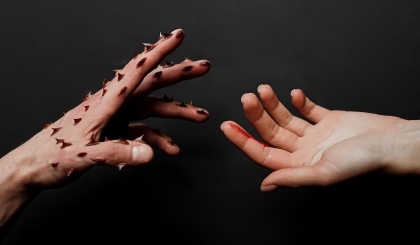 One hand with attached thorns in hurting the other. Gender-based violence concept.